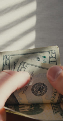 Close-up of male hands counting 20 dollar bills, vertical shot