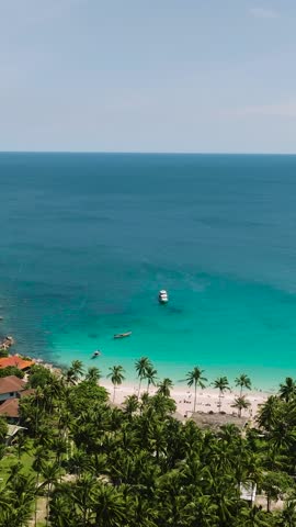 Aerial view of tropical bay with turquoise waters, boats, and lush green hills surrounding the coastline. Ao Leuk, Koh Tao, Thailand.