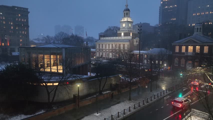 Aerial night view of Independence Hall with illuminated skyline of Philadelphia, showing historic landmarks and modern buildings in United States during winter. Rising shot. Cold dusk scene.