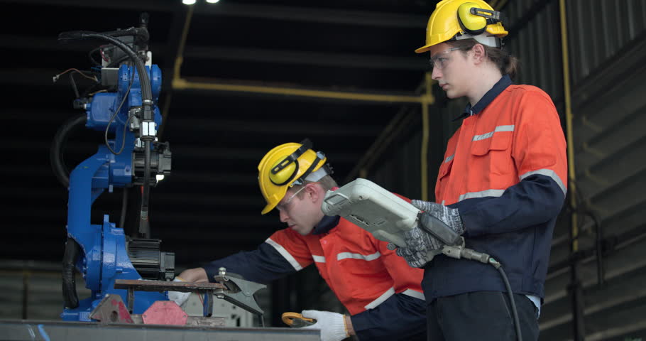 Two highly competent robotic operators collaborate to configure new automation using a computer-controlled panel display. The robot