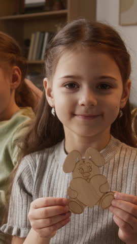 Vertical portrait of cheerful Caucasian girl child posing for camera holding handmade paper bunny