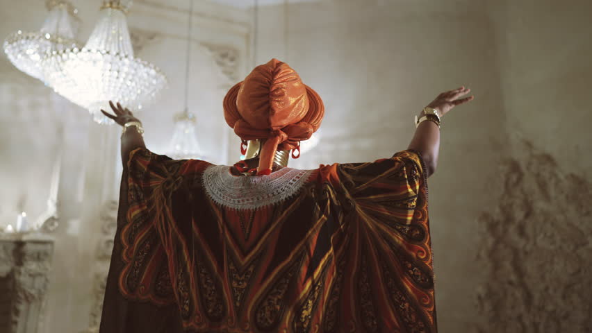 Back view of dancing woman, african shaman or priest praying, asking rain. Amazing dance performance in studio, unique african culture and traditions, bright ethnic gown and turban, unique aesthetics