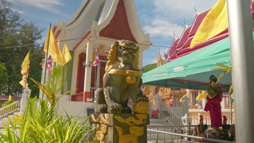 Close-up of a majestic guardian lion statue (Singha) at Wat Nai Harn temple. Features traditional Buddhist architecture and Thai national flags in the background. 4K cinematic travel footage.