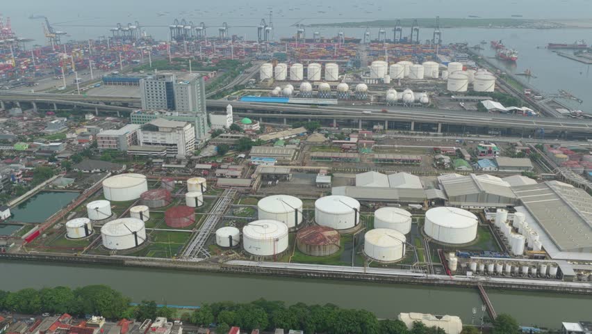 Aerial perspective of an industrial tank terminal and pipeline network in Jakarta, illustrating large-scale storage infrastructure near major transport routes.