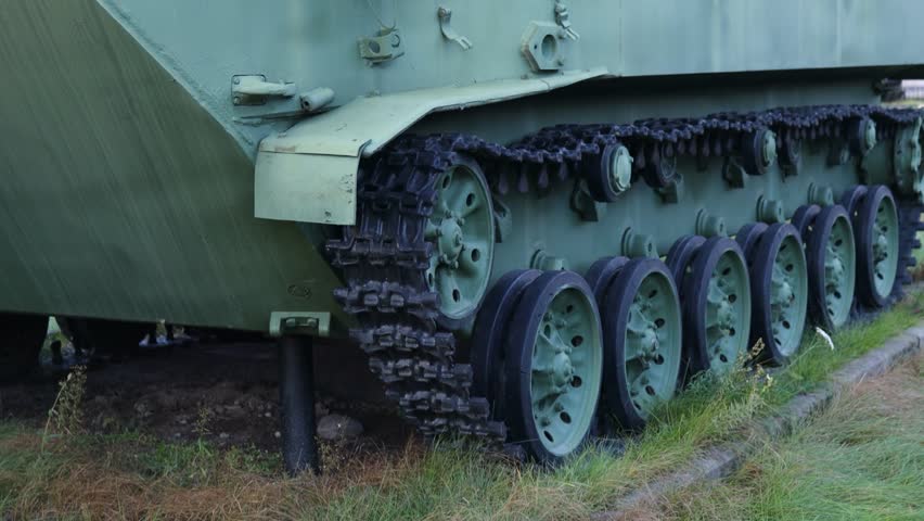 A close-up view of a military tank sitting on a green field, ready for action.