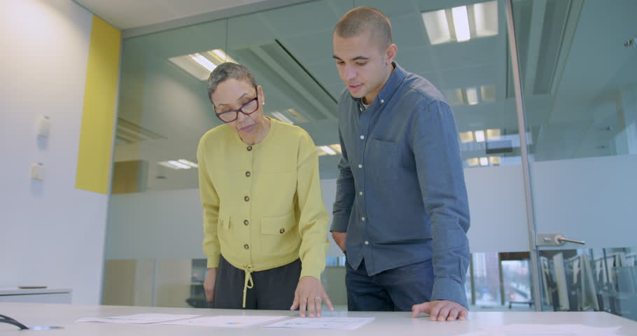 Two Businesspeople Analyzing Data Together on a Table in Meeting room