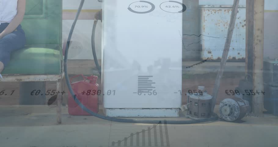 Animation of graphs and currency values over caucasian woman talking on cellphone by gasoline pistol. Digital composite, business, finance, economy, fuel, gas station, natural gas, service.