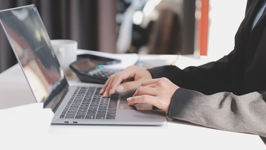 Closeup of the hands of a receptionist typing and sending emails while working in an office alone. One secretary doing admin and writing reports while organizing a schedule for her manager at work