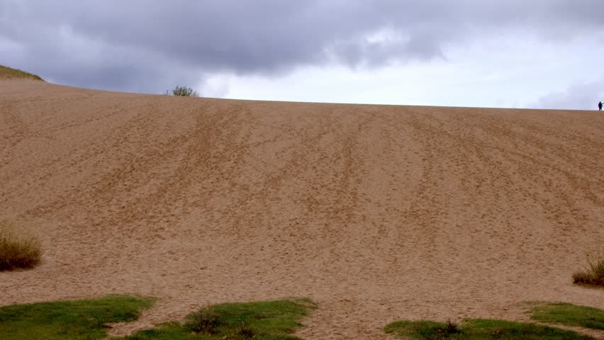 Middle aged man walking up Dune Climb at the Sleeping Bear Dunes National Lakeshore in Michigan with stable video shot.
