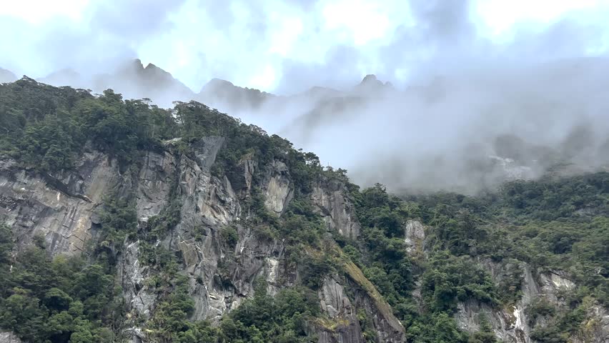 Foggy dramatic mountain peaks with rocky cliff, Milford Sound, New Zealand landscape