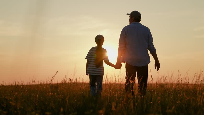 Family picnic in park. Dad walks with little daughter on grass, sunset. Happy family travels plays in sun park. Childhood dream travel. Dad, kid daughter relaxing in nature. Father raising child girl