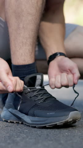 Person, hands and tying with shoes for fitness, workout preparation or running safety on road. Closeup, active or runner getting ready with sneakers or laces for sprint, race or training on asphalt