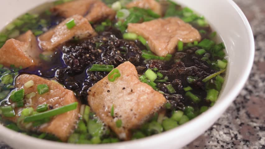 A comforting bowl of tofu, seaweed, and fresh green onions simmers in a savory broth. 