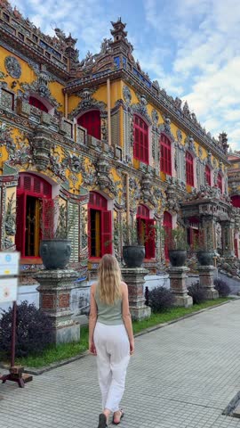 Woman walking along ornate palace facade in the Imperial City of Hue, Vietnam, showcasing historic architecture, cultural heritage, and authentic travel experience in central Vietnam.
