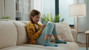 Gadget addict Caucasian little child girl using mobile phone at home kid happy smiling scrolling smartphone technology relaxing on sofa daughter watching funny video in social media smile in apartment - Powered by Shutterstock - Get 15% off with code: PIKWIZARD15
