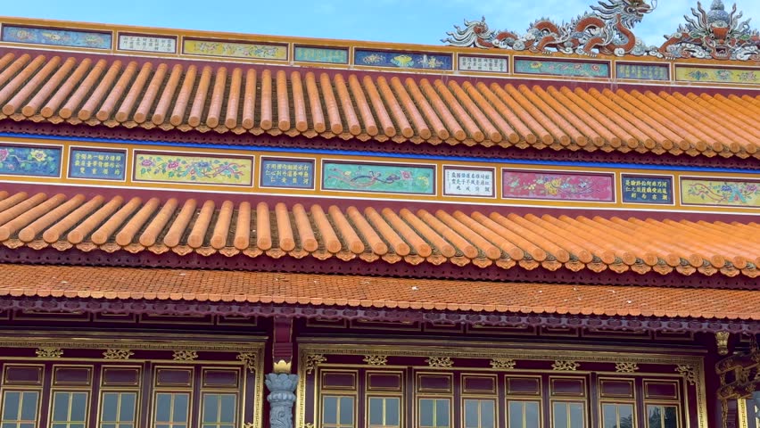 Detailed view of an ornate palace facade inside the Imperial City of Hue, Vietnam, featuring traditional tiled roof, decorative elements, and historic Vietnamese architecture.