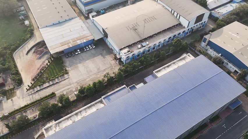 Wide aerial shot of a modern warehouse facility, emphasizing renewable power generation, large-scale industry, and sustainability within a landscaped industrial campus.