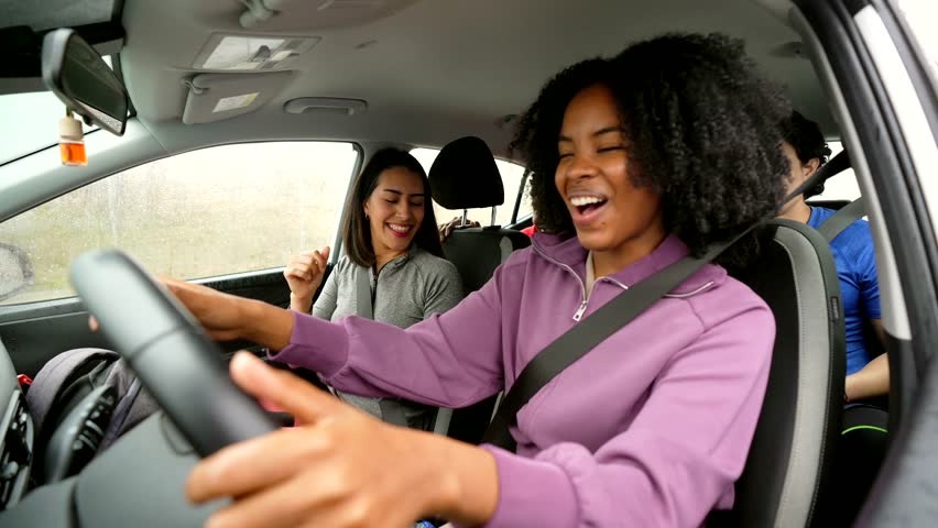 Energetic group of diverse friends joyfully dancing and singing while driving a car, having fun together on a road trip before or after playing pickleball, feeling happy and carefree