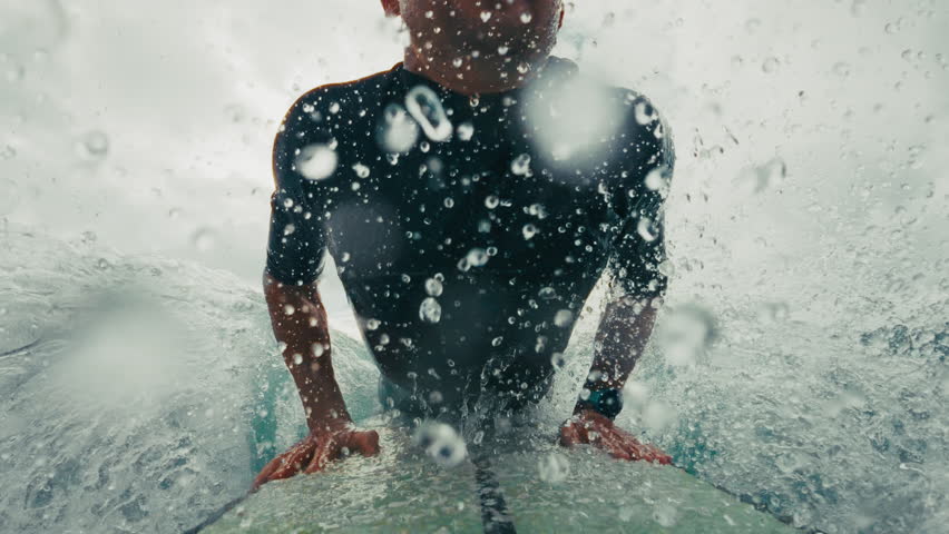 Surfer in wetsuit rides the wave in Atlantic Ocean. Surfboard camera view of the surf rider