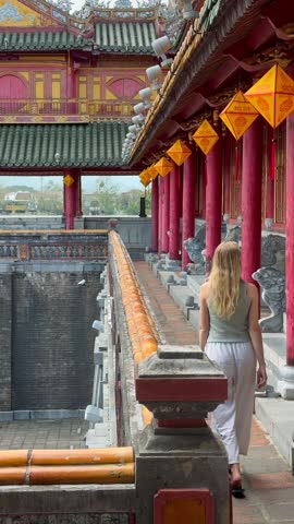Woman walking along ornate palace facade in the Imperial City of Hue, Vietnam, showcasing historic architecture, cultural heritage, and authentic travel experience in central Vietnam.