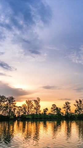 Golden Sunset Over Tranquil Lake With Tree Reflections and Dramatic Sky