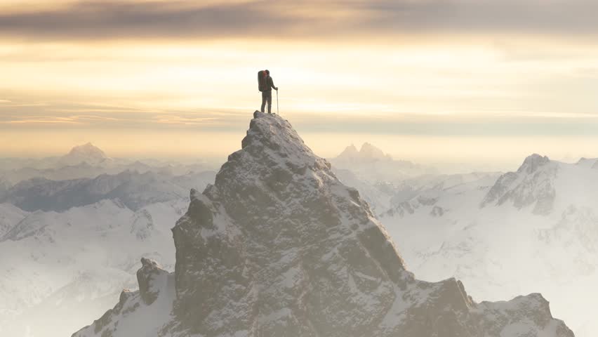 Solitary Adventurer Stands on Snowy Mountain Peak, Achieving Success Above a Grand Alpine Landscape