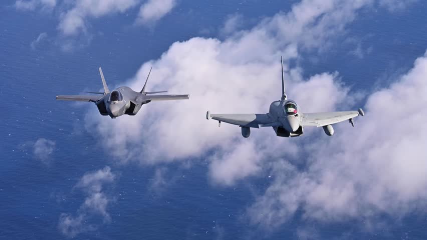 Two Military Fighter Jets Flying in Formation Above Clouds and Ocean