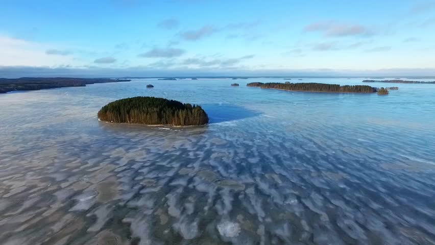 Aerial View of Serene Islands in a Vast Icy Lake with Gentle Sky Reflections and Patterns in Finland
