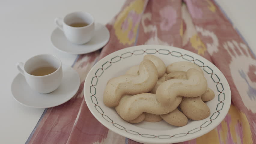 Cosy morning with a plate with biscuits and cups of coffee on white table with colored cloth , peaceful day 