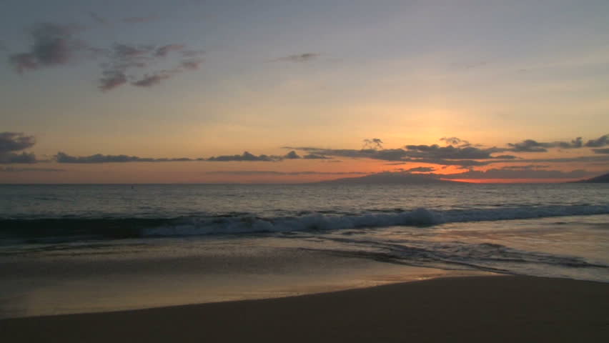 Waves crashing on pacific ocean with sun set behind horizon.
