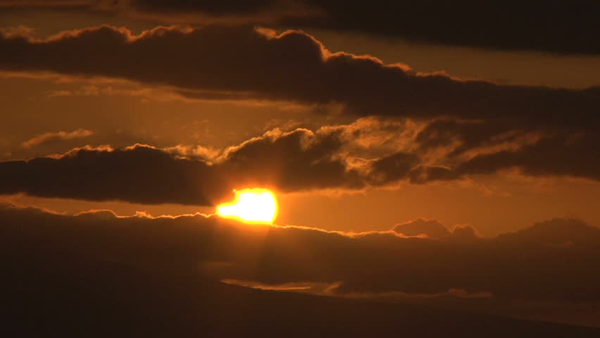 Time lapse with sun rising behind clouds, close up.