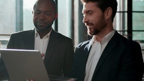 Two smiling men diversity businessmen business team with laptop talking enjoying pleasant communication work with computer Caucasian businessman expert showing idea consulting African American leader - Powered by Shutterstock - Get 15% off with code: PIKWIZARD15