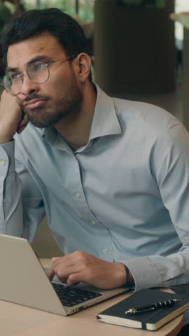 Ethnic Indian business man sad pensive thinking with laptop come up with idea solution good decision think businessman guy male with computer working solving problem web task work hesitate in cafe