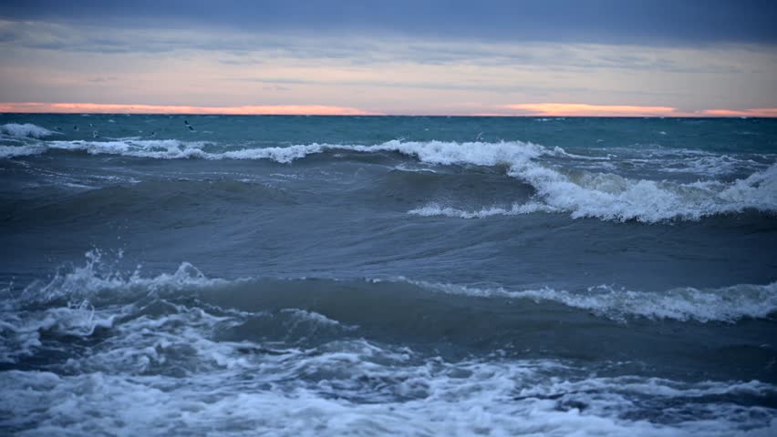 Waves Crash on Shore as Clouds Gather During Sunset in a Dramatic Coastal Landscape