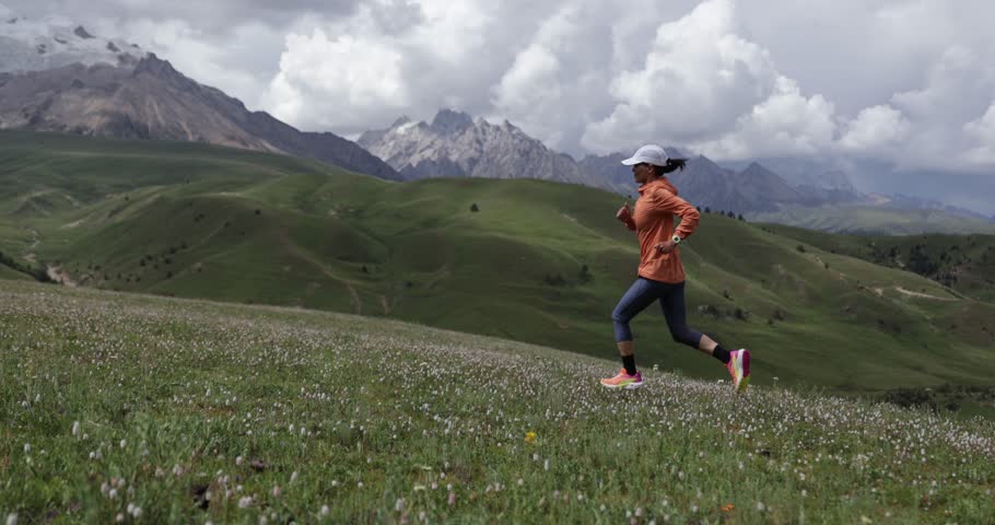 Trail runner running on the high altitude grassland mountain top, slow motion