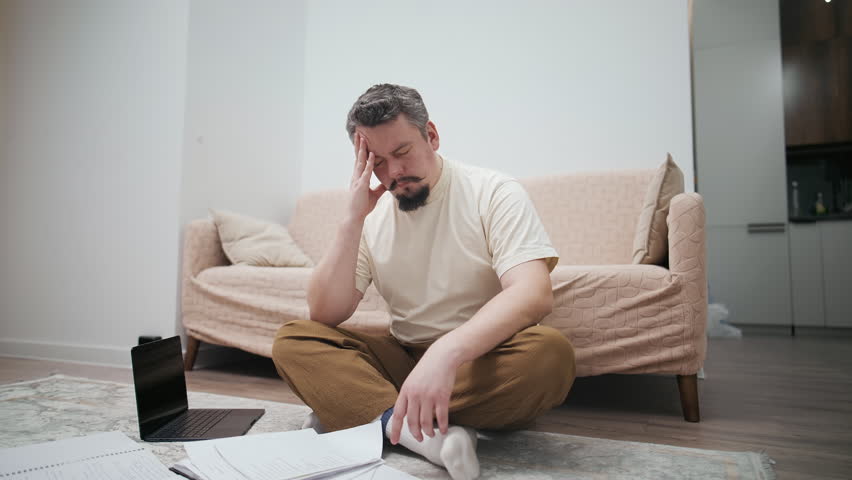 Stressed middle-aged man suffering from a headache at home
