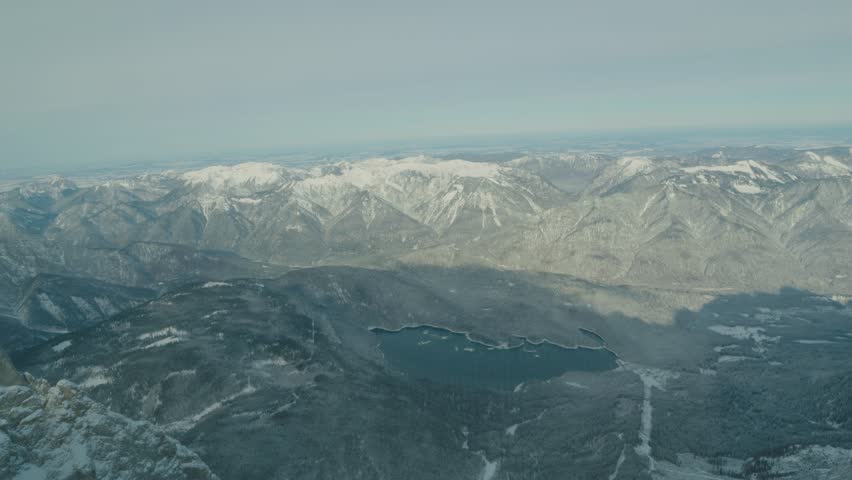 A stunning panoramic view of snow-covered mountains surrounding a serene lake, showcasing the beauty of nature. The landscape invites tranquility and exploration, perfect for outdoor enthusiasts and p