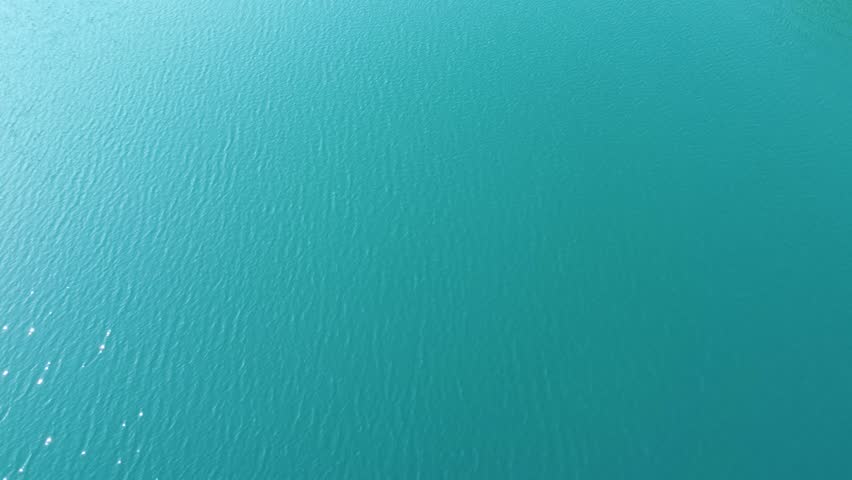 Clear blue lake surrounded by green forest and rocky shoreline in a peaceful natural setting.