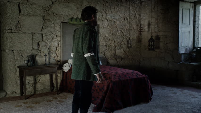 A person walks around an old room with a simple bed and stone walls. Sunlight enters through the window, highlighting the details of the space. It feels like a step back in time.