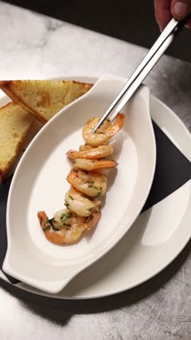 The chef prepares large prawns in the kitchen.