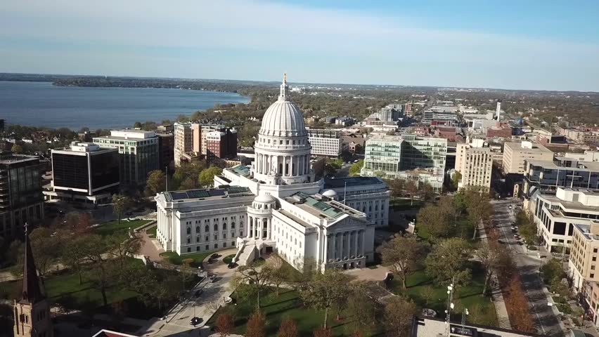 Aerial view of capitol building surrounded by city and greenery.