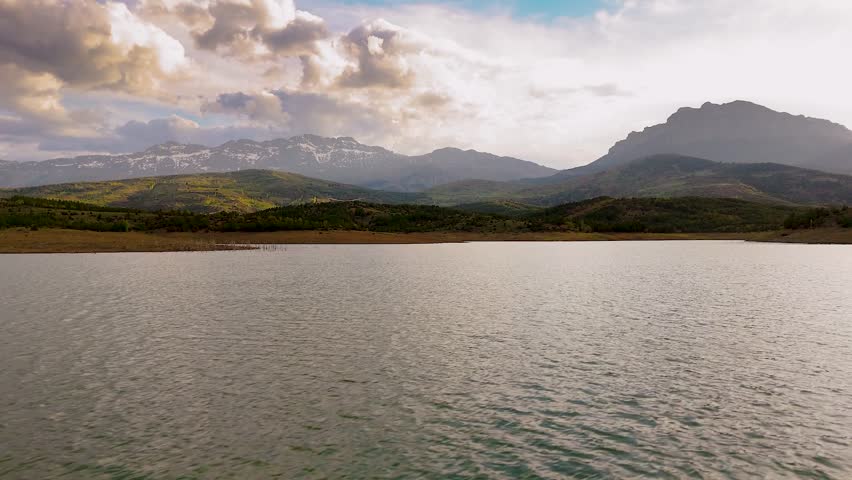 Peaceful mountain lake landscape with clouds and natural scenery.
