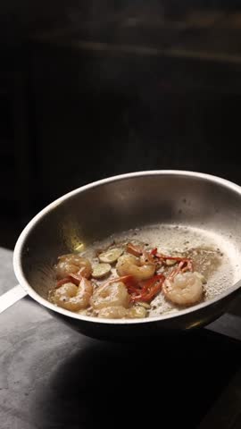 The chef prepares large prawns in the kitchen.