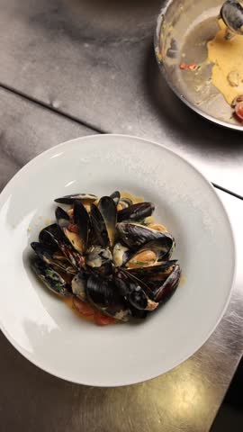 The chef prepares mussels in the kitchen.