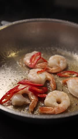 The chef prepares large prawns in the kitchen.