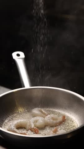 The chef prepares large prawns in the kitchen.