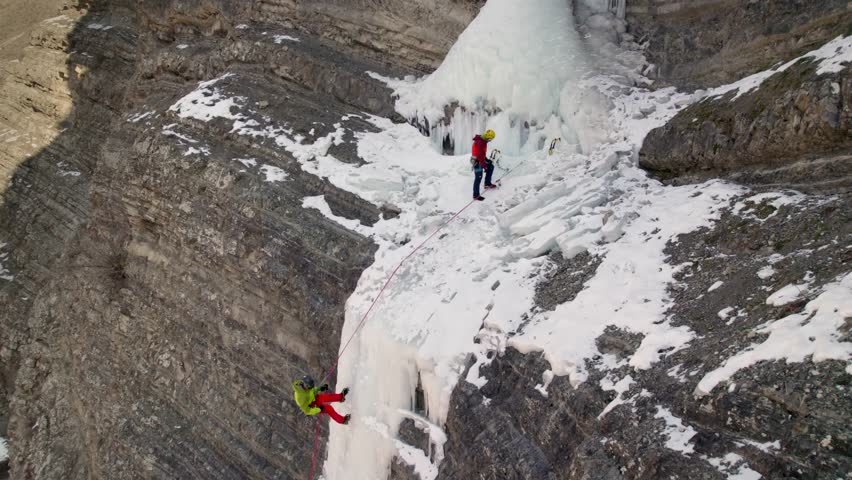 Two mountaineers ice climbing on a frozen waterfall.