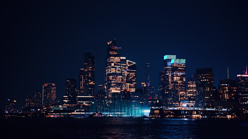 Midtown Manhattan skyline at night. Midtown Manhattan skyscrapers glow with city lights against a dark night sky.