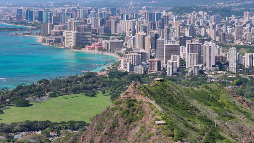 Peak of Diamond Head with people overlooking Waikiki Beach aerial view, tall buildings by the ocean coast, Honolulu city , Hawaii