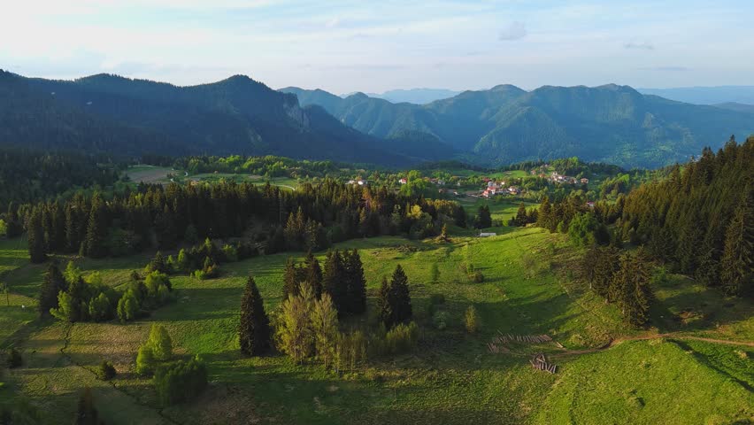 Mountain valley sheltered by vegetation and spruce forests with village of Smolyan with meadows where sheep graze